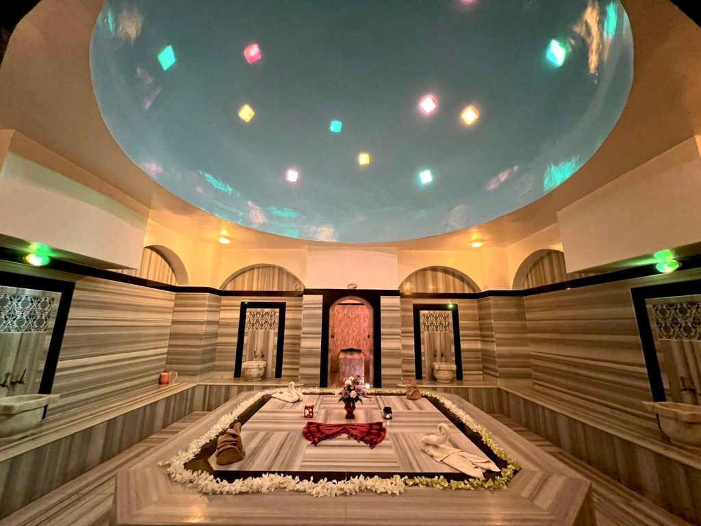 nterior view of a luxurious Turkish Bath (Hammam) in Hurghada featuring a warm marble stone (Gobek Tasi) and atmospheric lighting