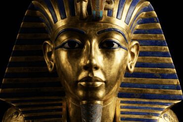 The famous Golden Death Mask of King Tutankhamun shining in the dark, representing the treasures of the Egyptian Museum.